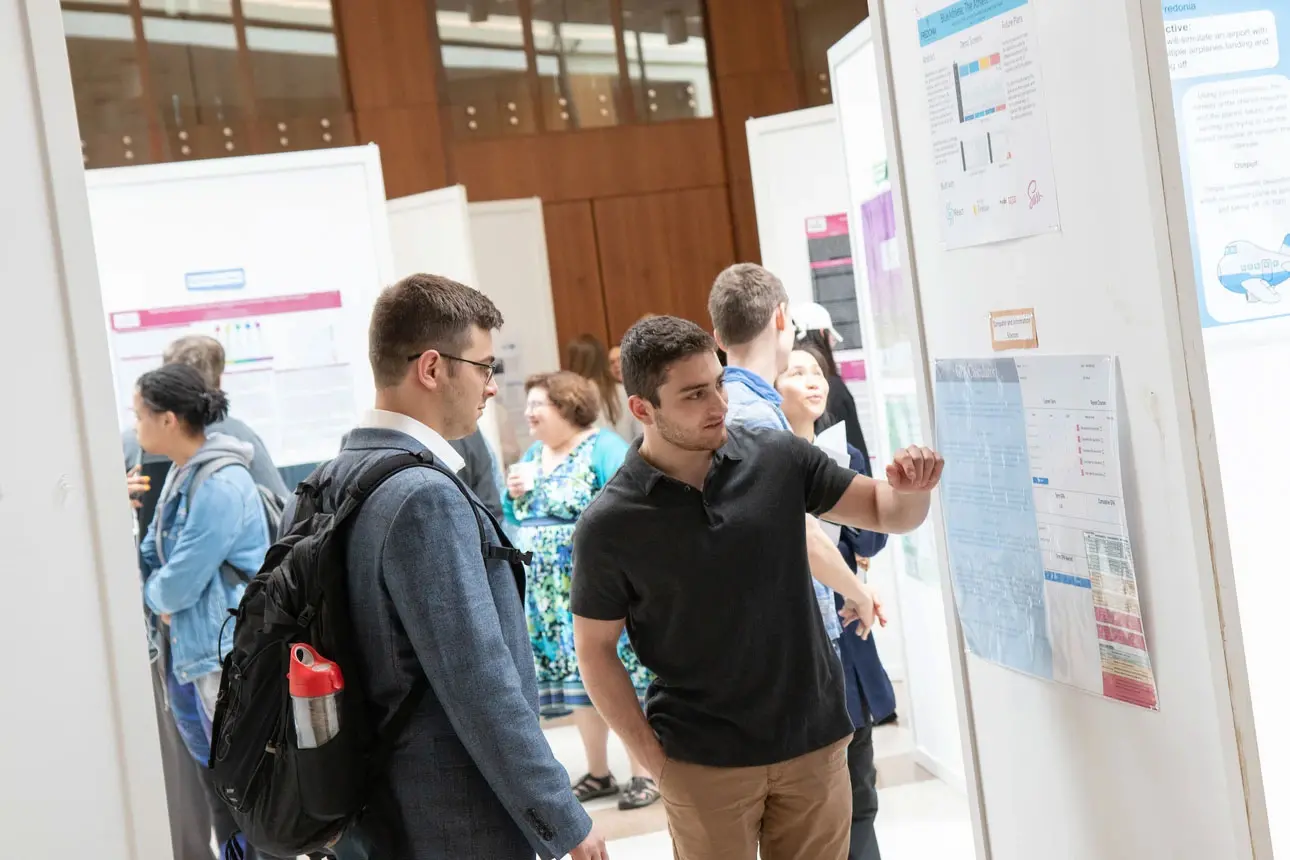 Students discuss research poster at OSCAR 2019