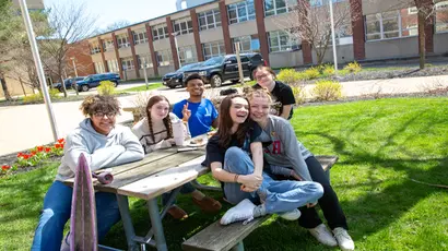 Fredonia students gather at a picnic table on a gorgeous spring day