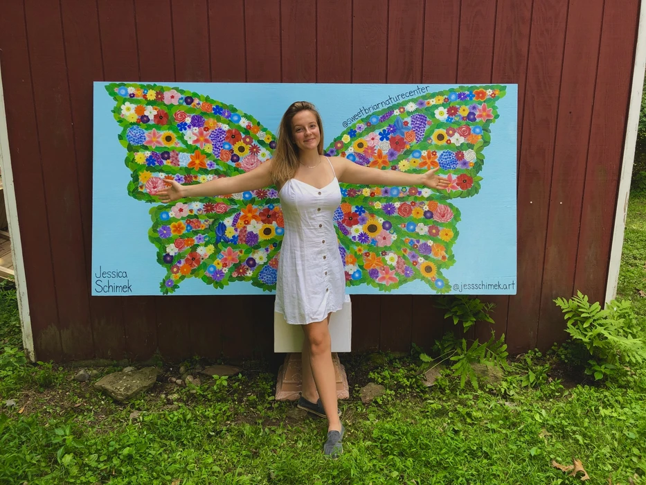 Jessica Schimek in front of butterfly mural