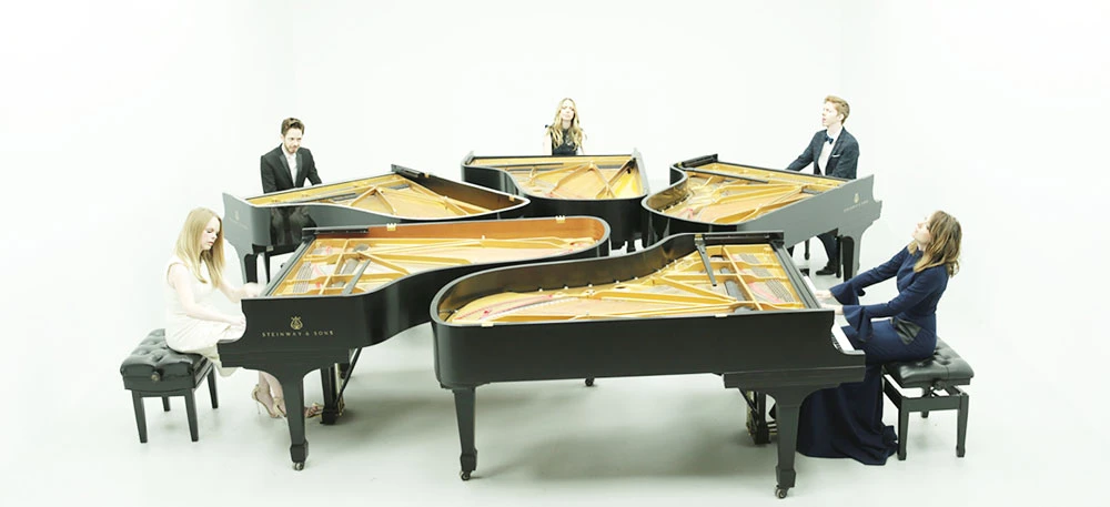 five pianos with people playing