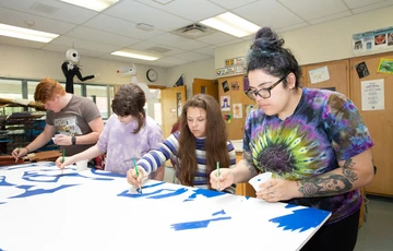 college students and middle schoolers work on art project