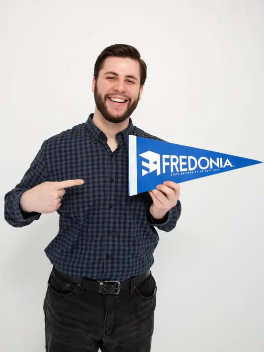 Luca Vukelic, a master's student in music, smiling with a FRED pennant 